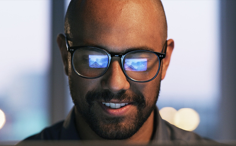 Man in glasses reviewing his screen