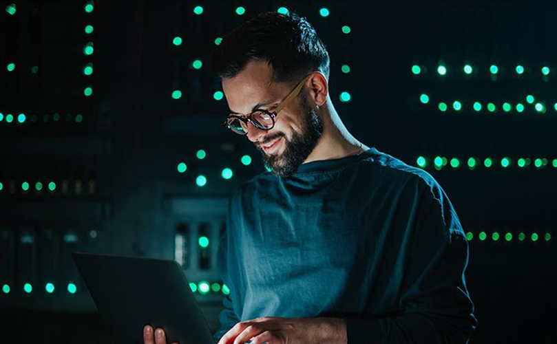 Man wearing glasses looking down at a device 