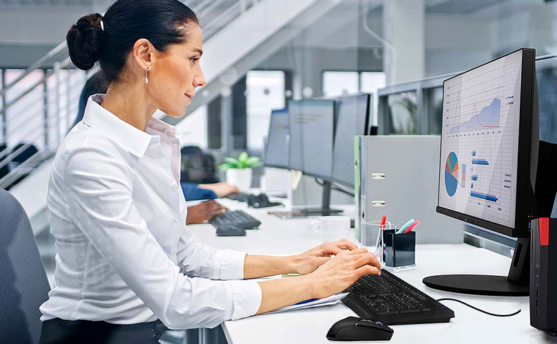 Nainen istuu pöydän ääressä ja työskentelee tietokoneella