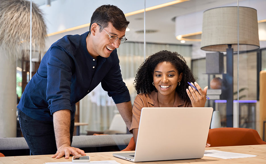 ラップトップを前に笑顔で話す男女2人組。
