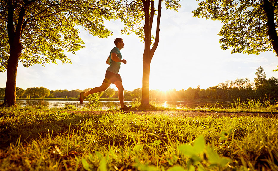朝焼けの湖畔をジョギングする男性