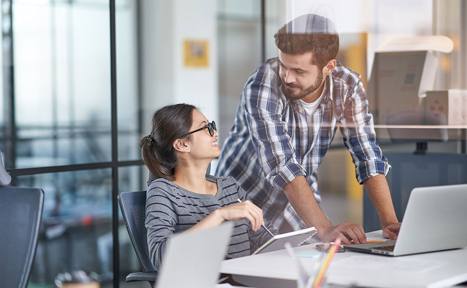 オフィスで笑顔で話し合い、協力する男女。