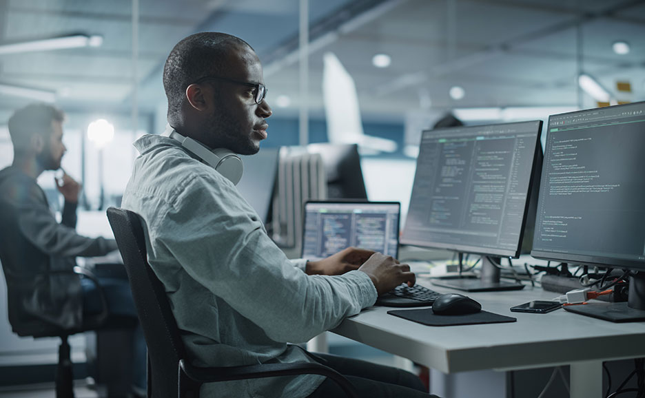 オフィスでモニターを見ながらキーボードを打つ男性。