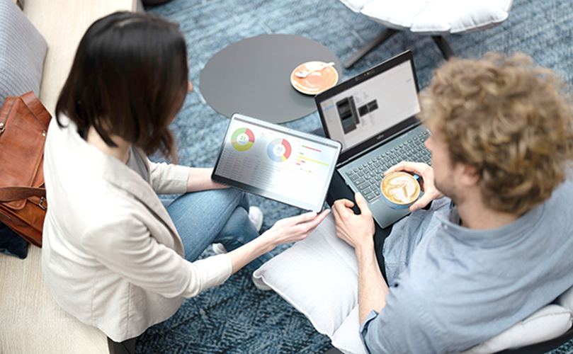 A man and woman relax on a couch, sharing a moment of laughter and conversation in a cozy living room setting.