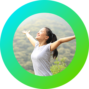 A happy woman, standing in the sunshine with outstretched arms, in front of a forest