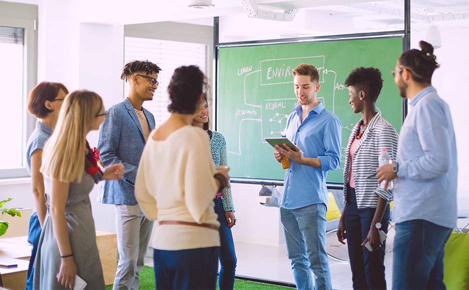 タブレットを持った人を中心に男女のグループで笑顔で会話している様子