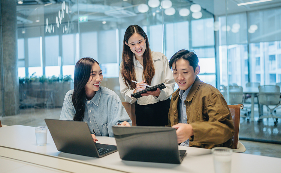 3人組の男女のが笑顔でPCを見つめている様子