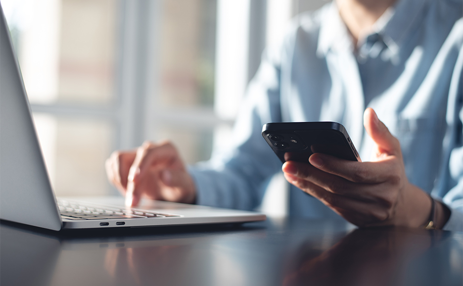 ラップトップとスマートフォンの両方を使用している人のイメージ