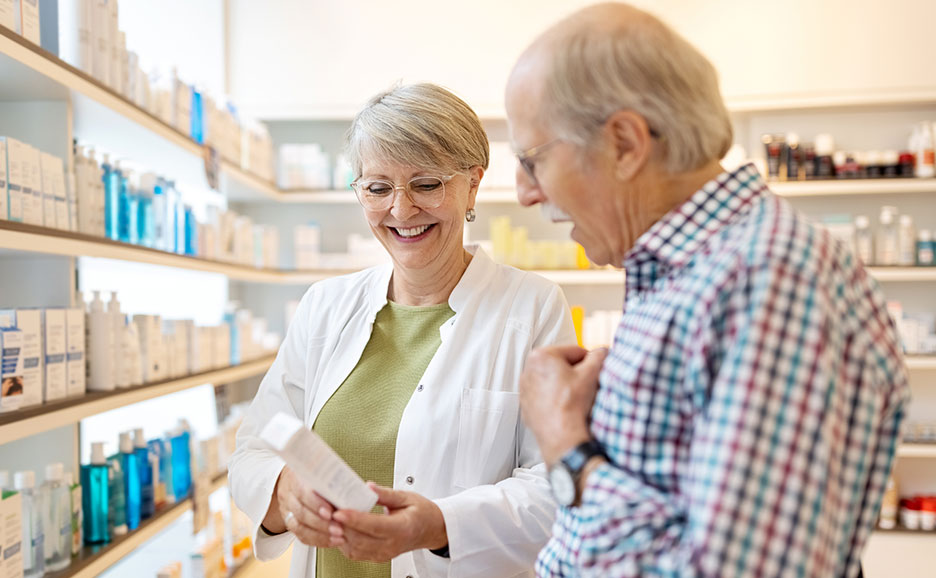 男性客が店頭で薬を買うのを手伝う笑顔の女性薬剤師