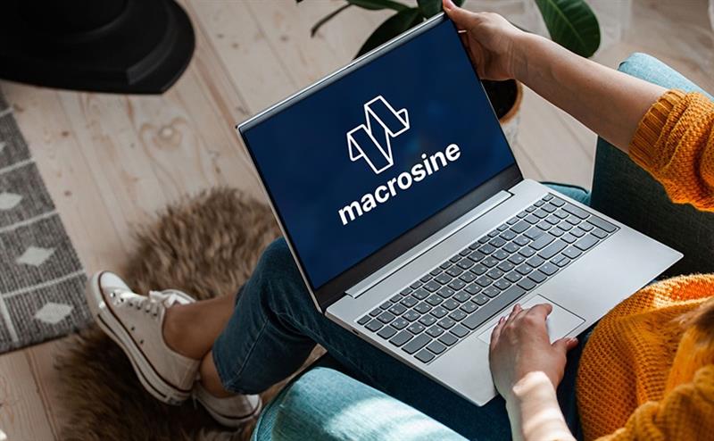 A person holding a laptop with the Macrosine logo displaying