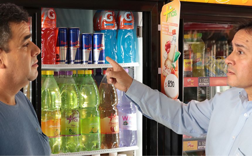 Imagem de dois profissionais próximos a uma máquina de venda de bebidas, conversando.