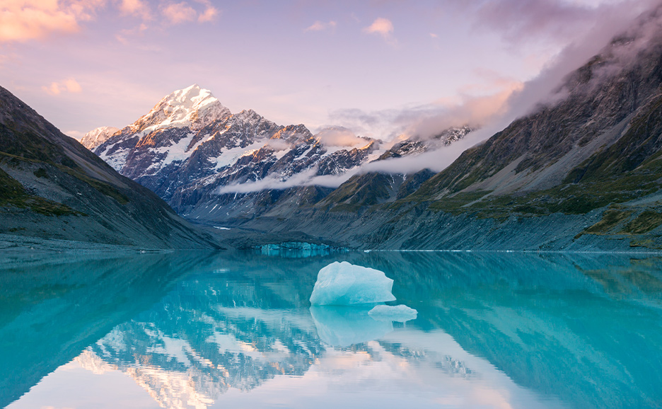 静かな湖に映る、雪を頂いたニュージーランド南島 クック山山頂の夕暮れ時 の写真​