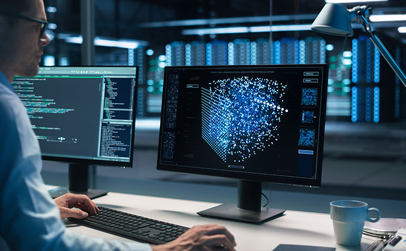 Side shot of male engineer working on desktop with screen showing statistics