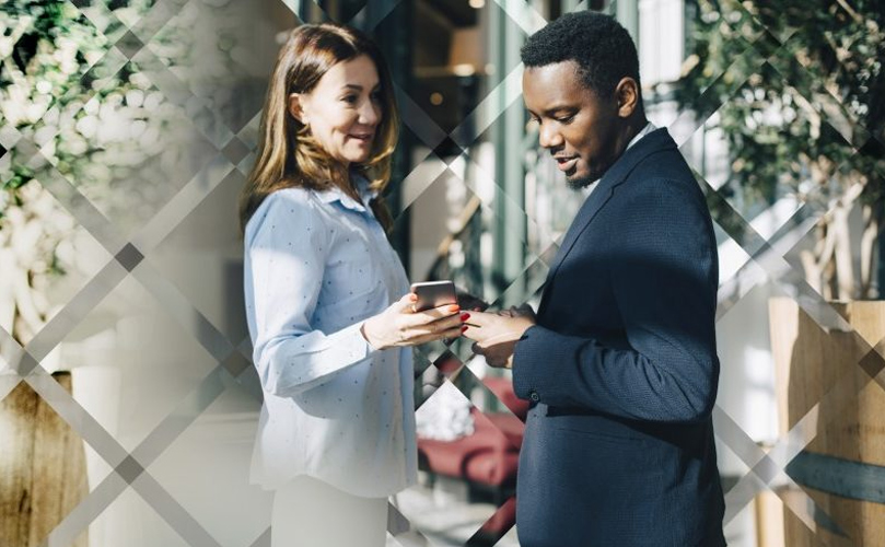 A man and a woman outdoors looking at a phone