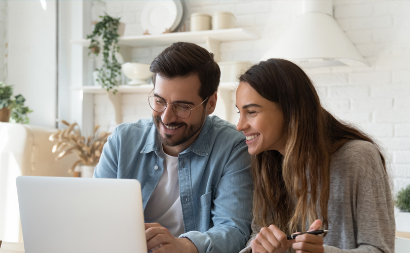 A man and a woman smiling at a computer