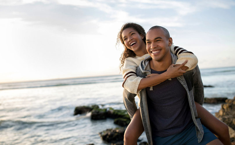 A woman piggyback on a man in the beach