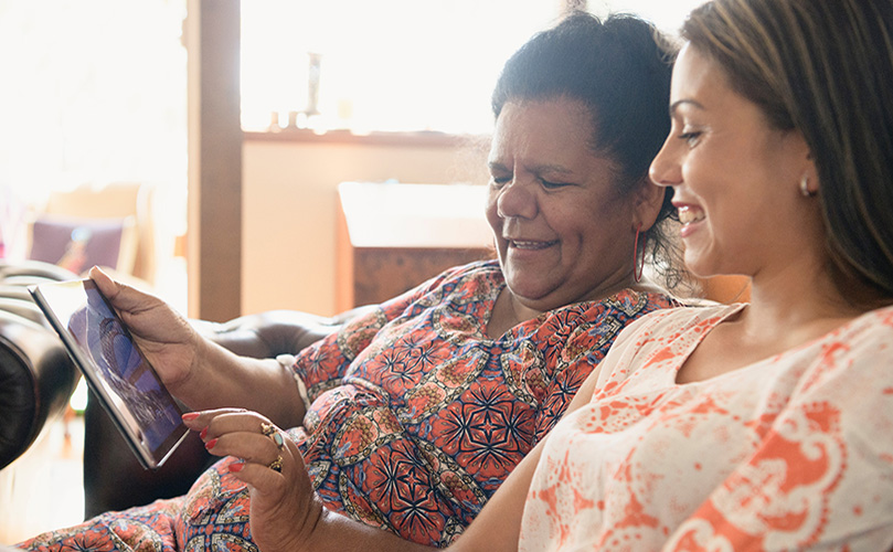 ผู้หญิงสองคนยิ้มและมองไปที่ไอแพด