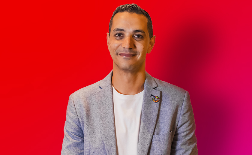 A man smiling looking at the camera in a red background