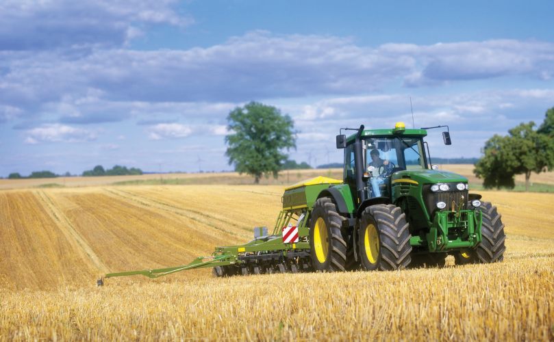 A man riding a tractor in the middle of a corn field