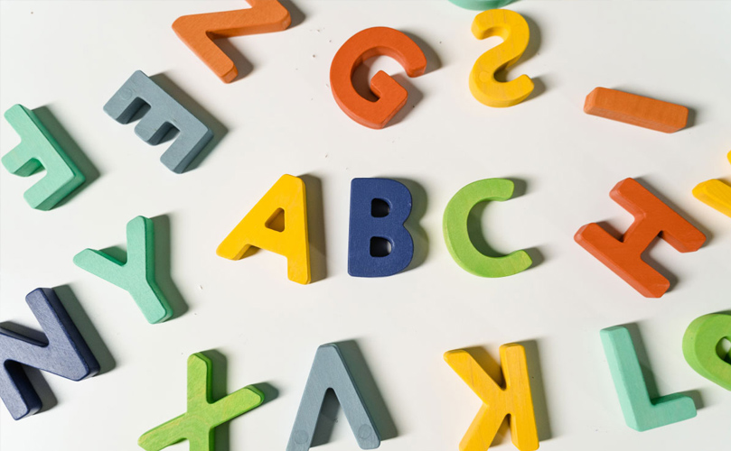 Letters of the alphabet spread out onto a surface and the middle reads 'ABC'