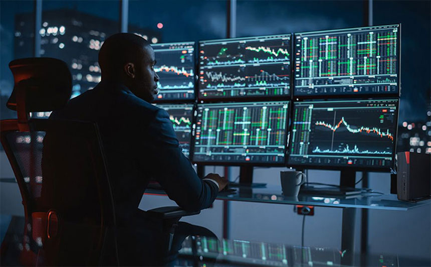 Finanzexperte betrachtet Börsencharts auf Computermonitoren im Büro