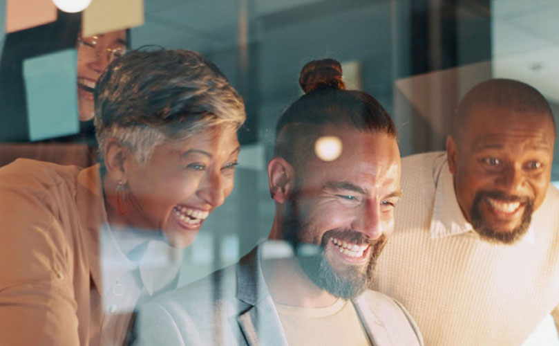 A group of colleagues engaged in a virtual meeting, smiling as they communicate and collaborate, connecting with others who are not physically present