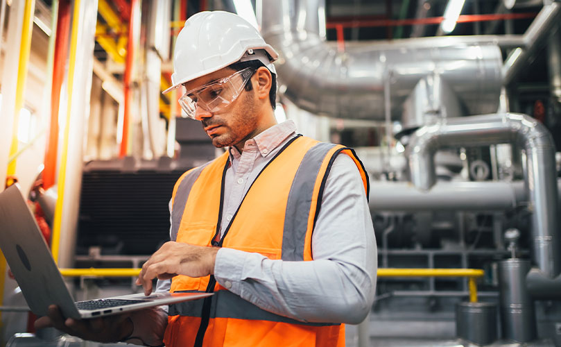 Techniker mit Schutzausrüstung überprüft Daten im Werk 