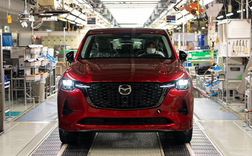 Um carro da marca 'Mazda' estacionado dentro de uma fábrica