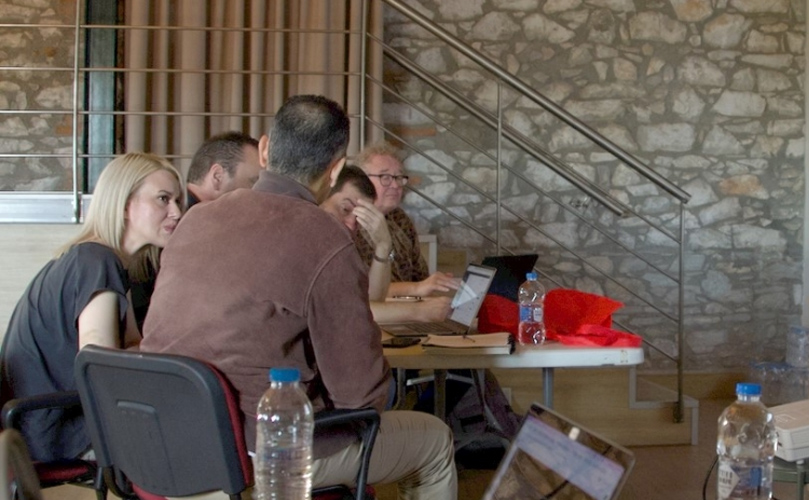 Several people gathered around tables, focused on their laptops