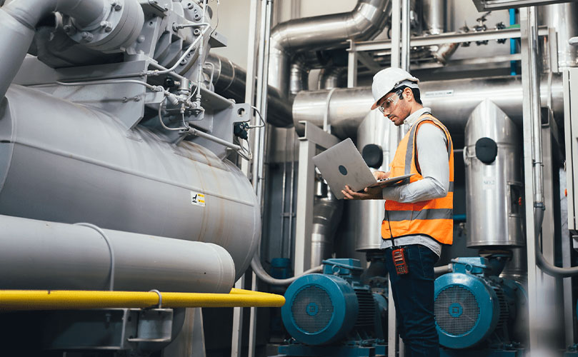 Ingenieur mit Laptop überprüft Industrieanlagen