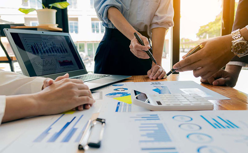 Pöytä täynnä papereita ja tietokone