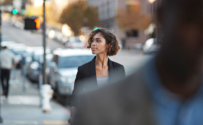 Woman walking in a city environment with focus on her and the background slightly blurred