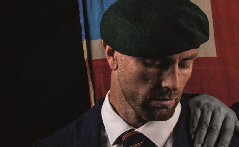 A man wearing a suit and a green beret stands confidently, showcasing a blend of formal attire and military style.