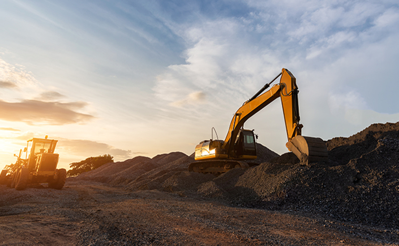 A yellow excavator in a pile of gravel