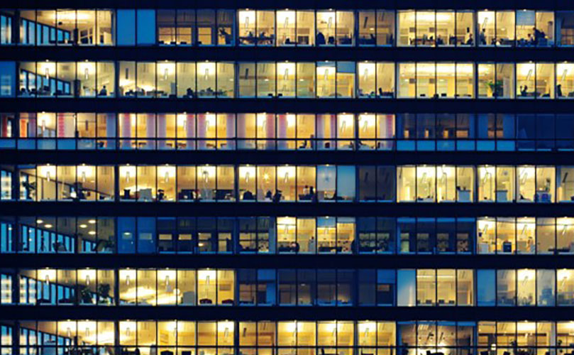 Building’s exterior at night. Numerous illuminated windows reveal various activities within.