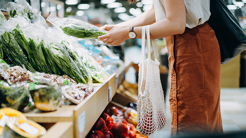 Woman with a carry bag shopping for fresh produce at a supermarket