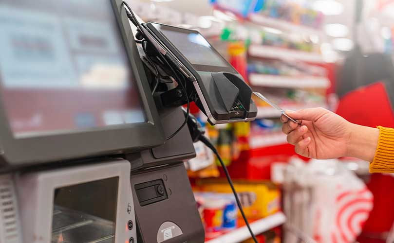 Kunde beim Bezahlen mit Kreditkarte an der Selbstbedienungskasse eines Supermarkts