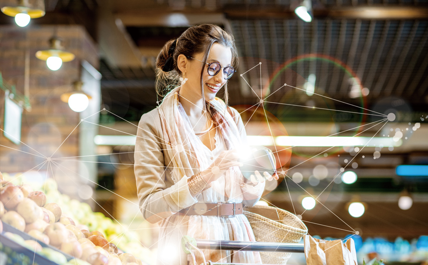 Wanita tersenyum di toko makanan melihat teleponnya