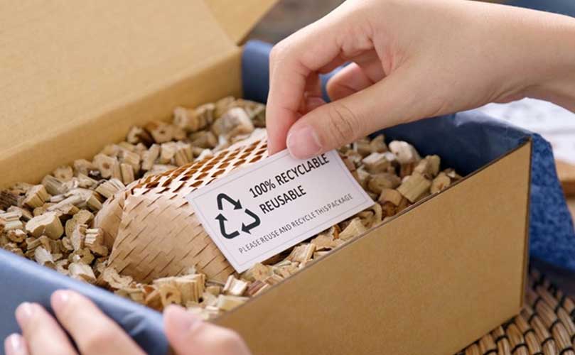 Hand placing recyclable labels on a package