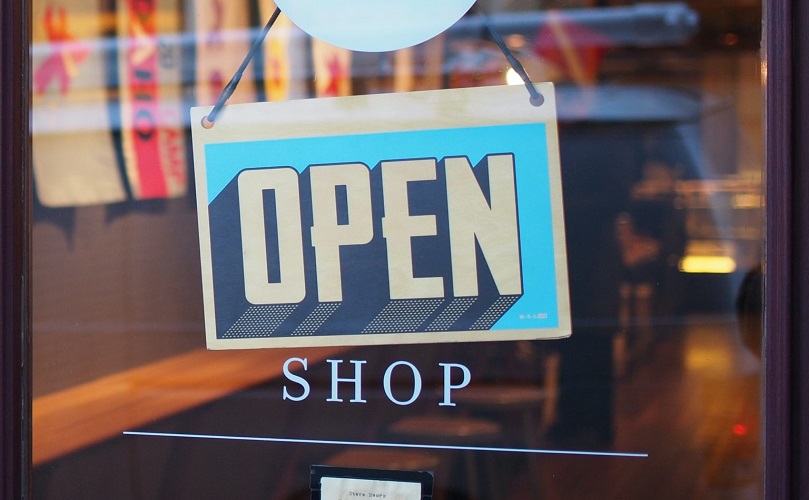Um sinal pendurado à porta de uma loja que diz "Open shop"