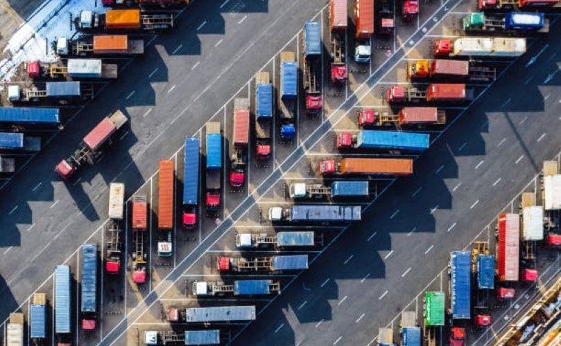 上空から見た、駐車場に整列した多数のカラフルなトラックとトレーラー。