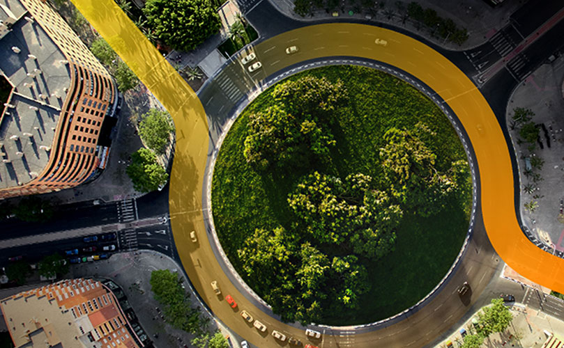 A roundabout with trees in a center, surrounded by buildings