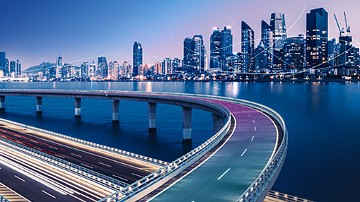 City skyline at night with a bridge spanning across the water.