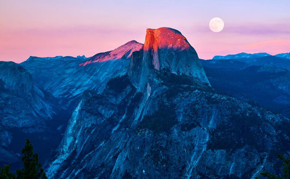 夕焼けに染まる山々、満月が空に浮かぶ雄大な風景。
