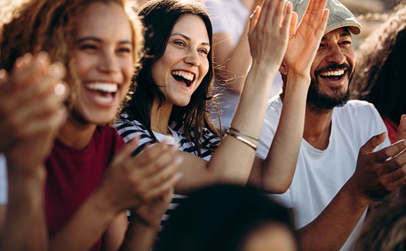 Audience members joyfully clapping at a concert, expressing appreciation for the live music and atmosphere.