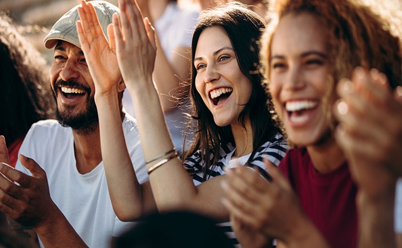 Audience members joyfully clapping their hands at a vibrant concert performance.