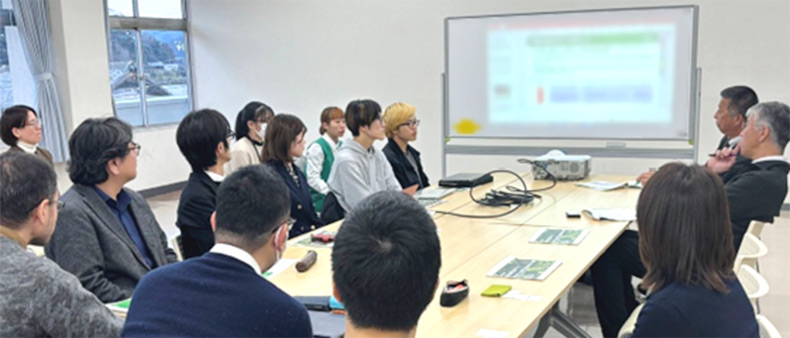 14名がプロジェクターで写し出された資料を基に議論している