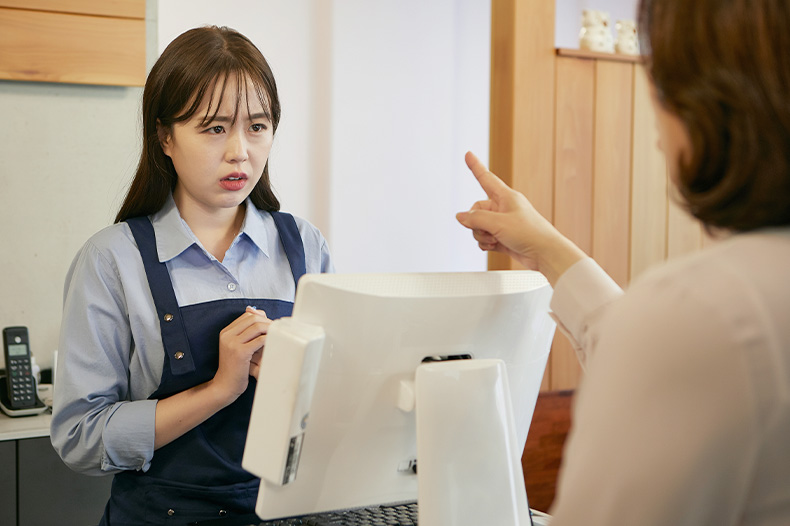 レジで接客する若い女性が、お客様からきつく当たられているイメージ写真