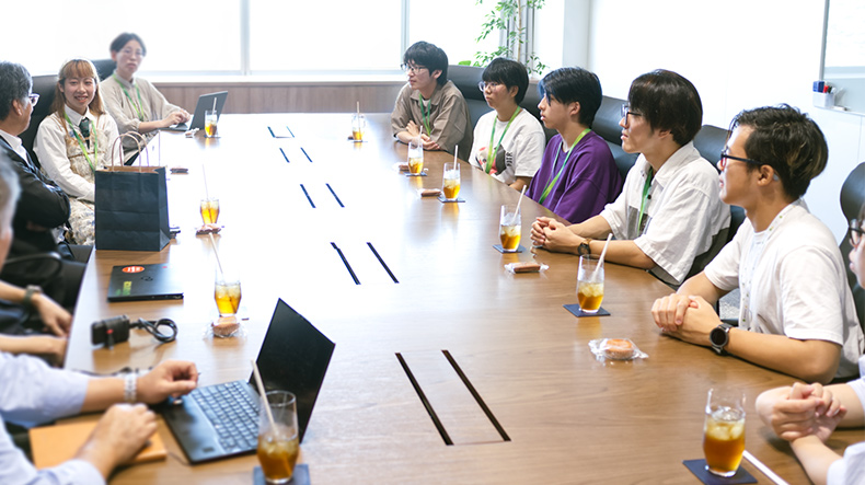 学生7名が長机に座り、お茶を飲みながら楽しそうに時田社長とお話している