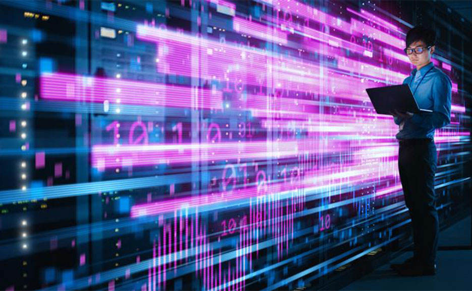 Ein Mann steht vor leuchtenden, fließenden Datenvisualisierungen in einem Rechenzentrum und arbeitet an einem Laptop